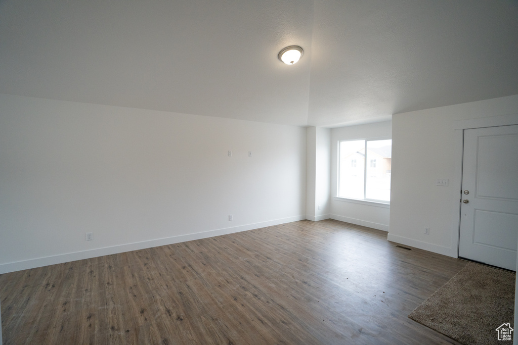 Unfurnished room with hardwood / wood-style flooring and vaulted ceiling