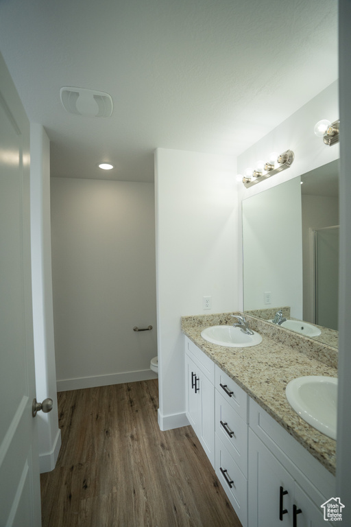Bathroom with hardwood / wood-style flooring, dual bowl vanity, and toilet