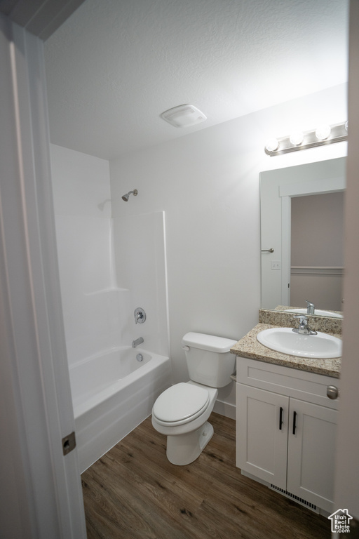 Full bathroom with hardwood / wood-style flooring, toilet, vanity, and shower / bathtub combination