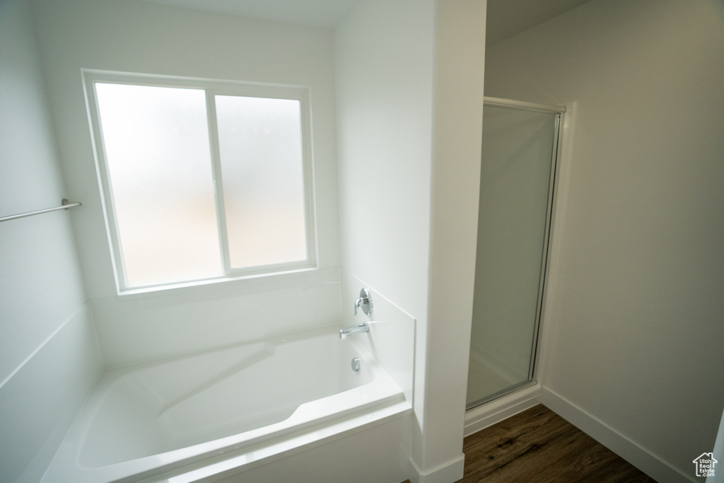 Bathroom featuring hardwood / wood-style floors, a wealth of natural light, and separate shower and tub