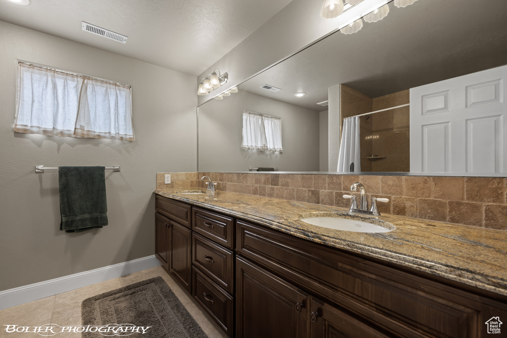Bathroom featuring tasteful backsplash, tile floors, and double sink vanity