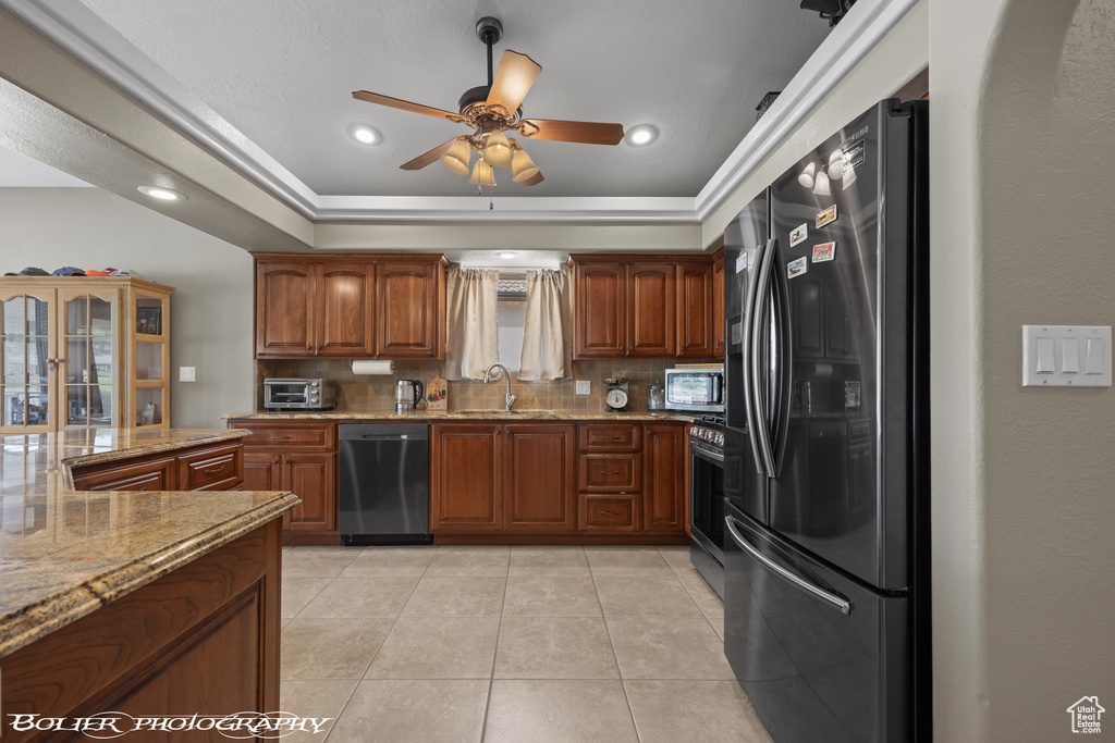 Kitchen with backsplash, ceiling fan, a raised ceiling, and stainless steel appliances