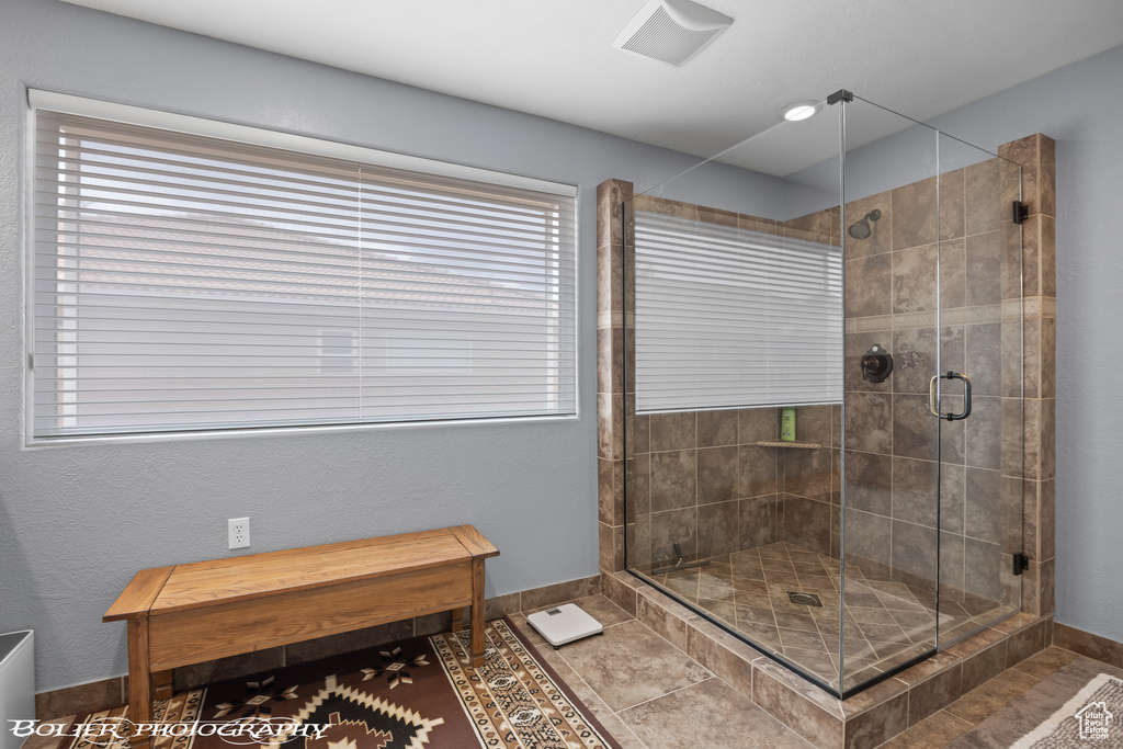 Bathroom featuring a shower with door and tile floors