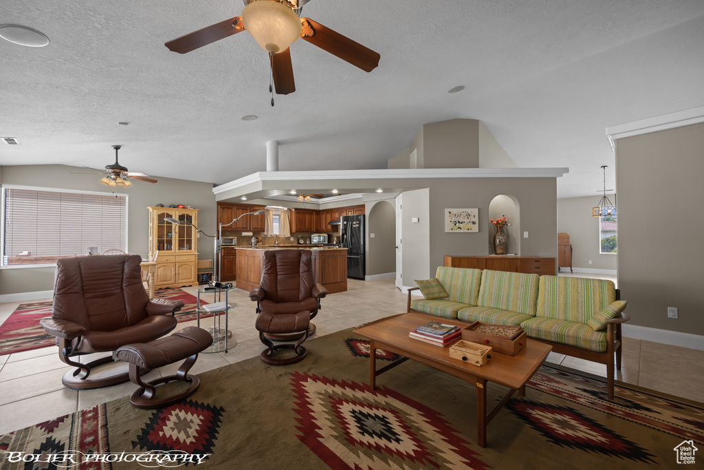 Tiled living room featuring high vaulted ceiling, ceiling fan, and a textured ceiling