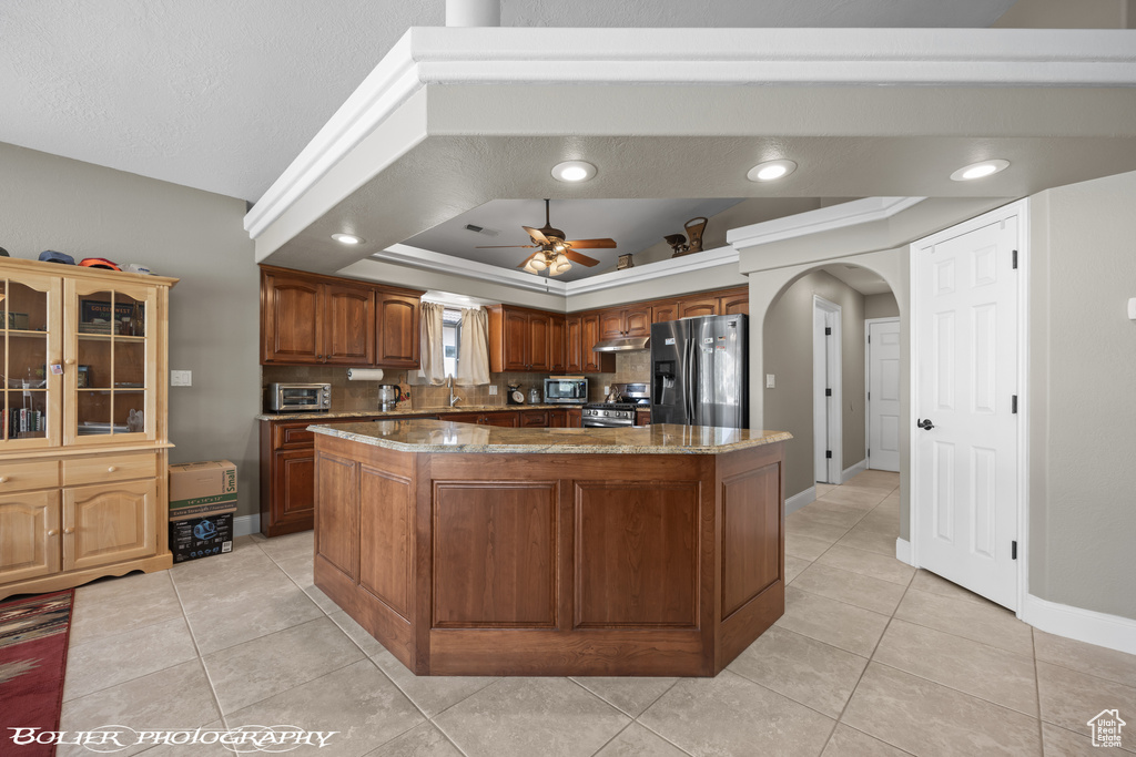 Kitchen featuring a center island, dark stone counters, stainless steel appliances, and a raised ceiling