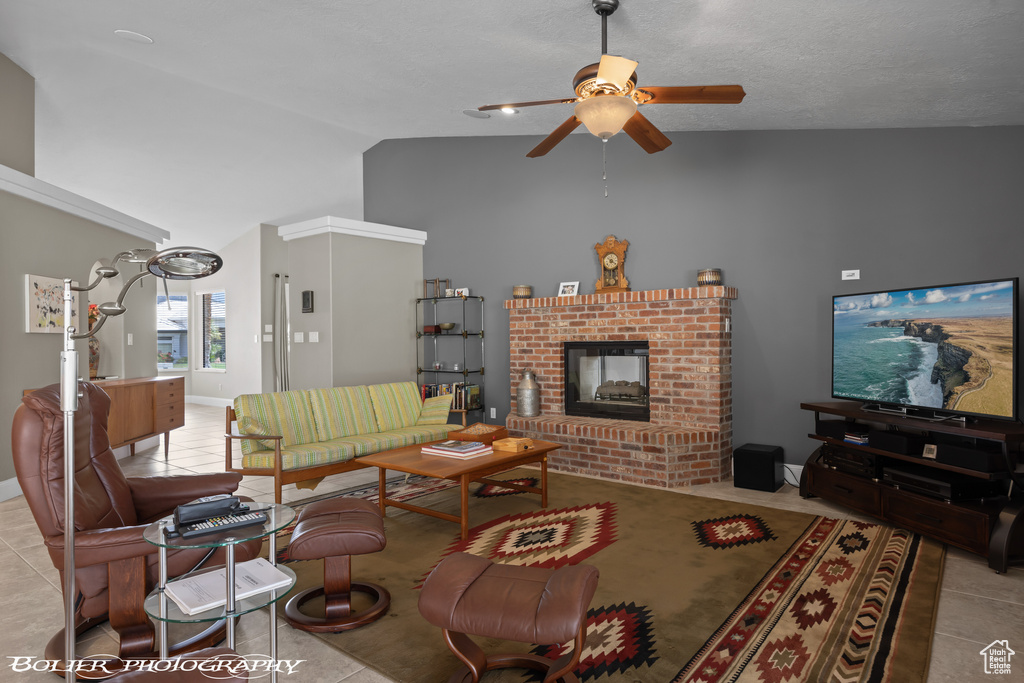 Tiled living room with high vaulted ceiling, ceiling fan, and a brick fireplace