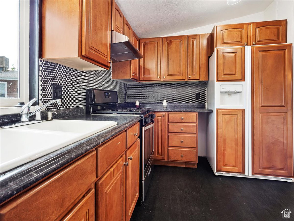 Kitchen with paneled fridge, wall chimney range hood, black range oven, lofted ceiling, and dark hardwood / wood-style floors