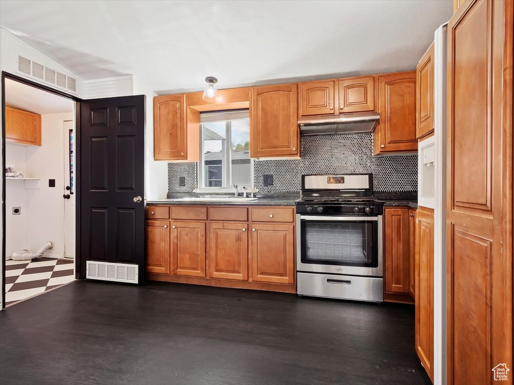 Kitchen with stainless steel stove, tasteful backsplash, and dark hardwood / wood-style flooring