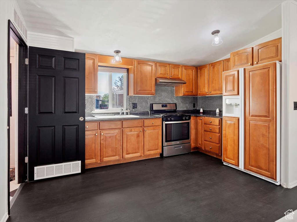Kitchen featuring paneled fridge, sink, stainless steel range with gas stovetop, and backsplash