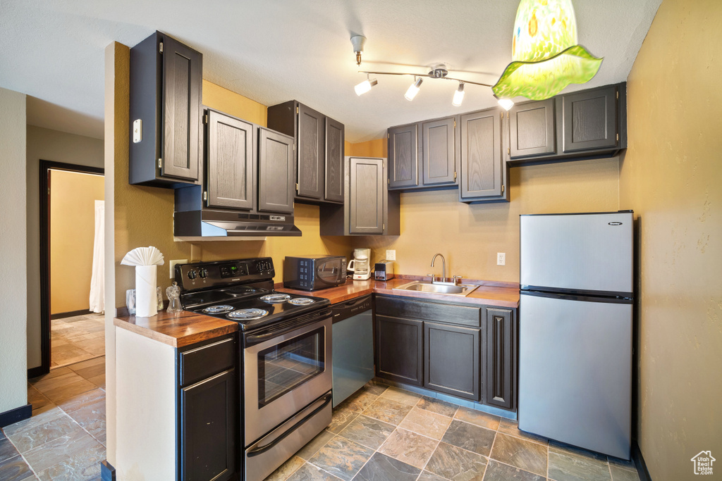 Kitchen with appliances with stainless steel finishes, sink, track lighting, and tile flooring