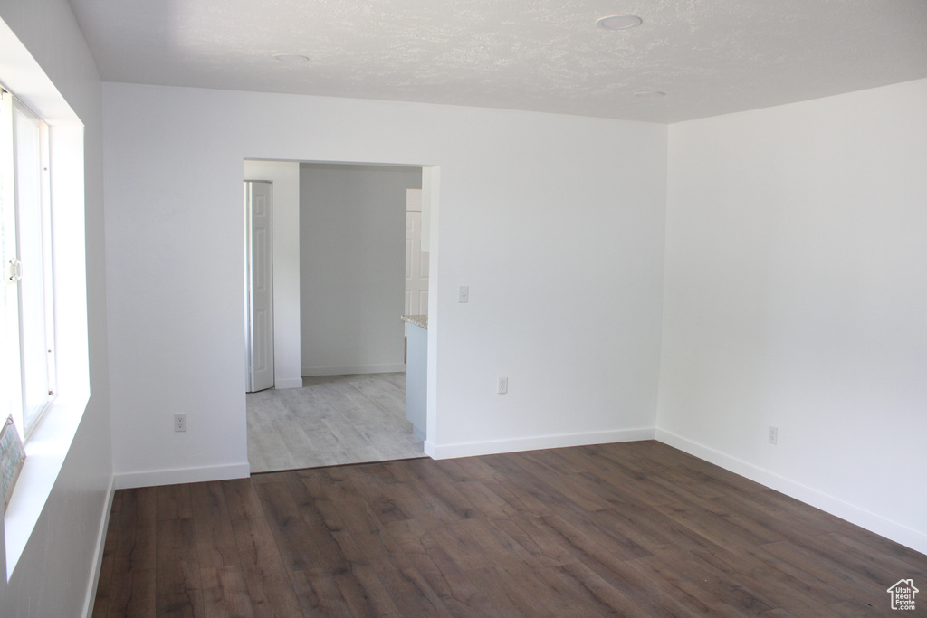 Empty room featuring dark hardwood / wood-style floors and a textured ceiling