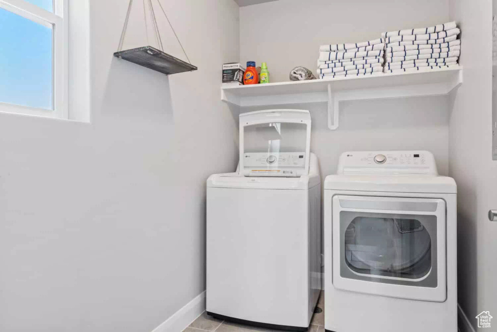 Clothes washing area featuring plenty of natural light, washer and clothes dryer, and light tile flooring