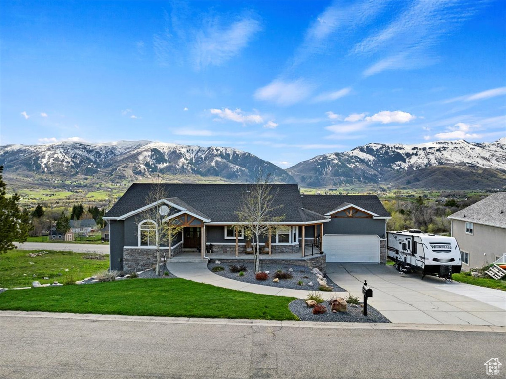 View of front of property with a garage, a porch, a mountain view, and a front lawn