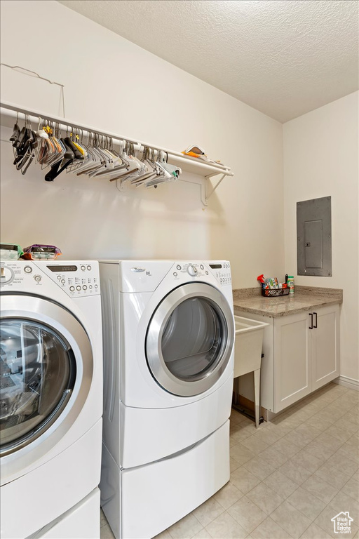 Laundry area featuring cabinets, light tile floors, washer and dryer, and a textured ceiling