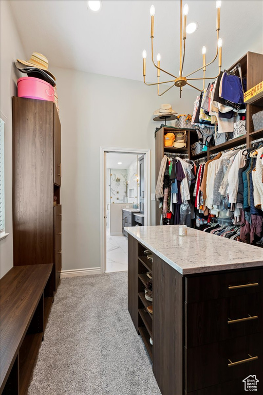 Walk in closet with an inviting chandelier and light carpet