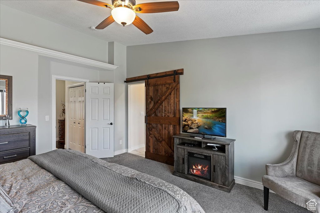 Carpeted bedroom featuring vaulted ceiling, ceiling fan, a textured ceiling, and a barn door