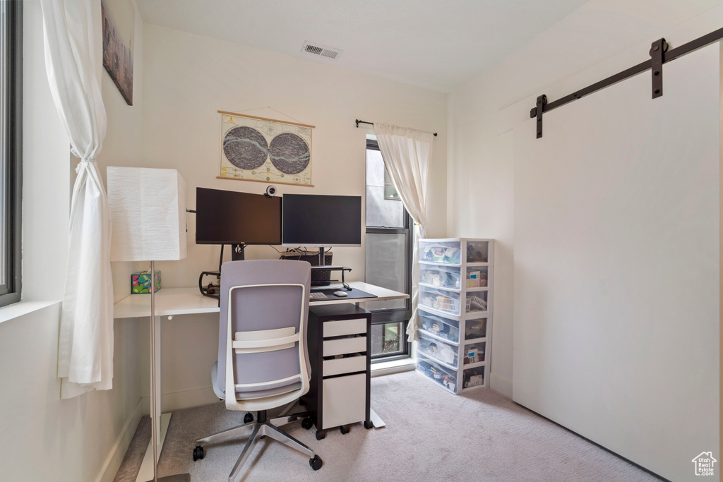 Home office featuring light colored carpet and a barn door