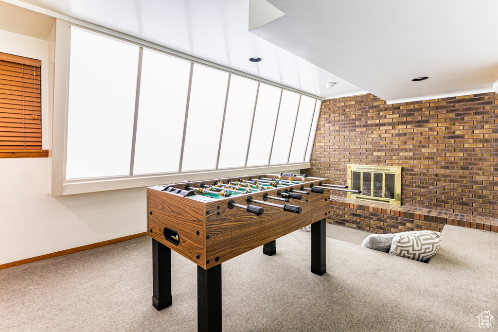 Playroom featuring brick wall, light carpet, and a brick fireplace