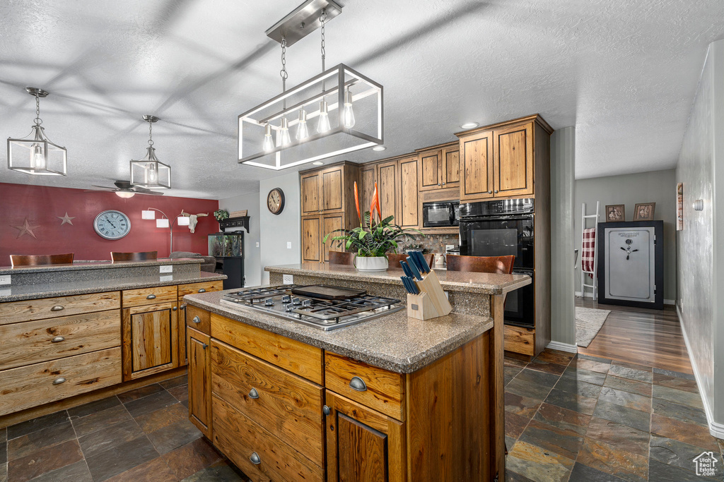 Kitchen featuring pendant lighting, dark tile floors, black appliances, a kitchen island, and ceiling fan