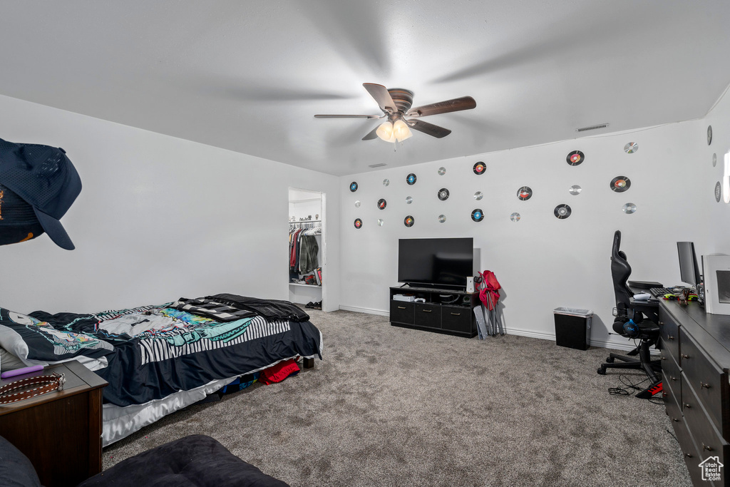 Bedroom with a closet, a spacious closet, carpet floors, and ceiling fan