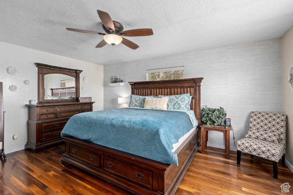 Bedroom featuring ceiling fan, dark wood-type flooring, and a textured ceiling