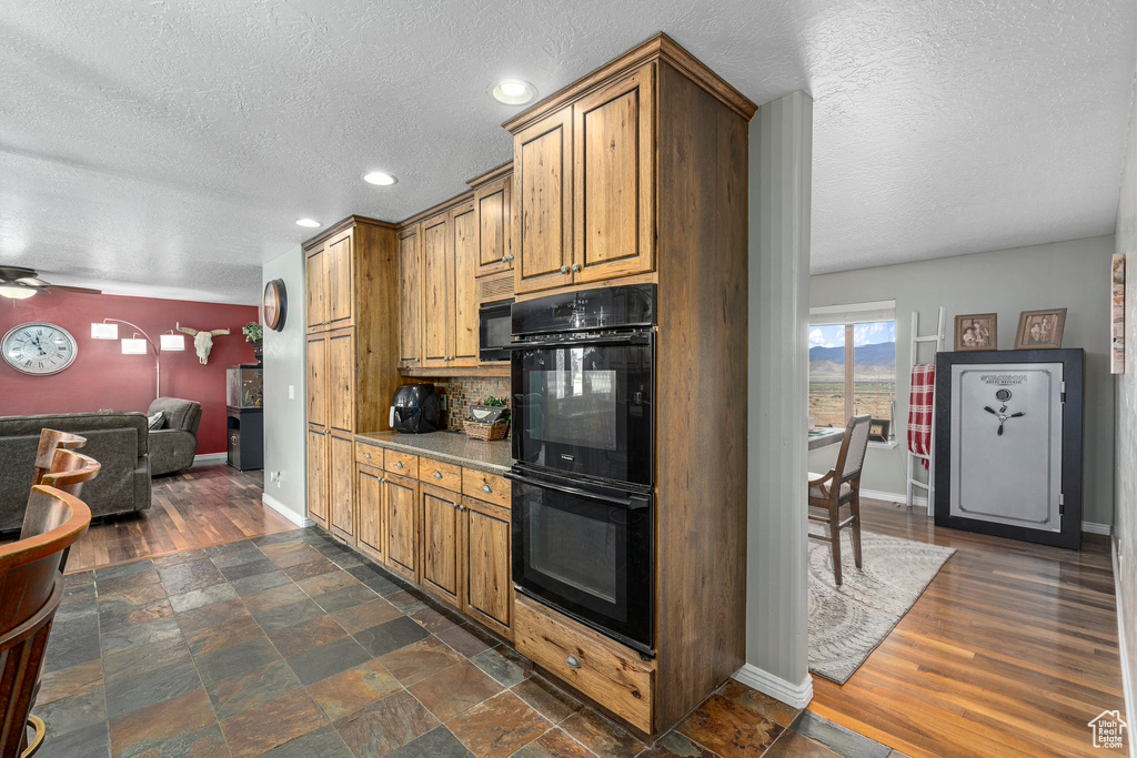 Kitchen with dark hardwood / wood-style flooring, ceiling fan, backsplash, and black appliances