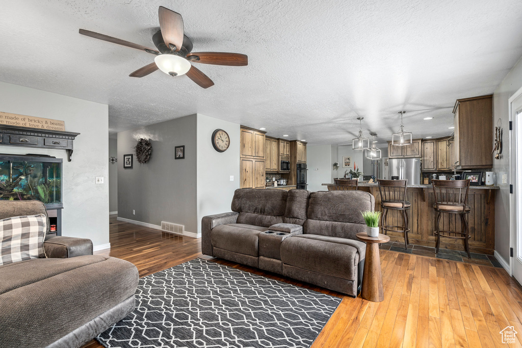 Living room featuring hardwood / wood-style flooring, ceiling fan, and a textured ceiling