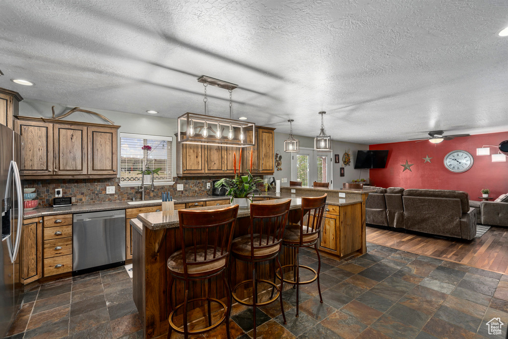 Kitchen with a kitchen island, plenty of natural light, ceiling fan, and stainless steel appliances