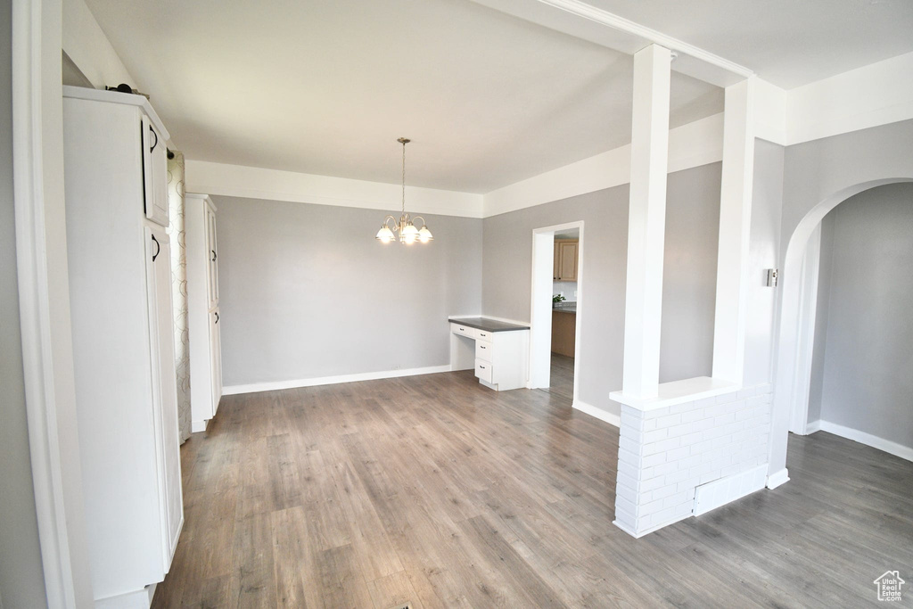 Empty room with a notable chandelier and hardwood / wood-style flooring