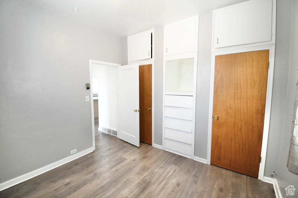 Unfurnished bedroom with a closet and hardwood / wood-style flooring