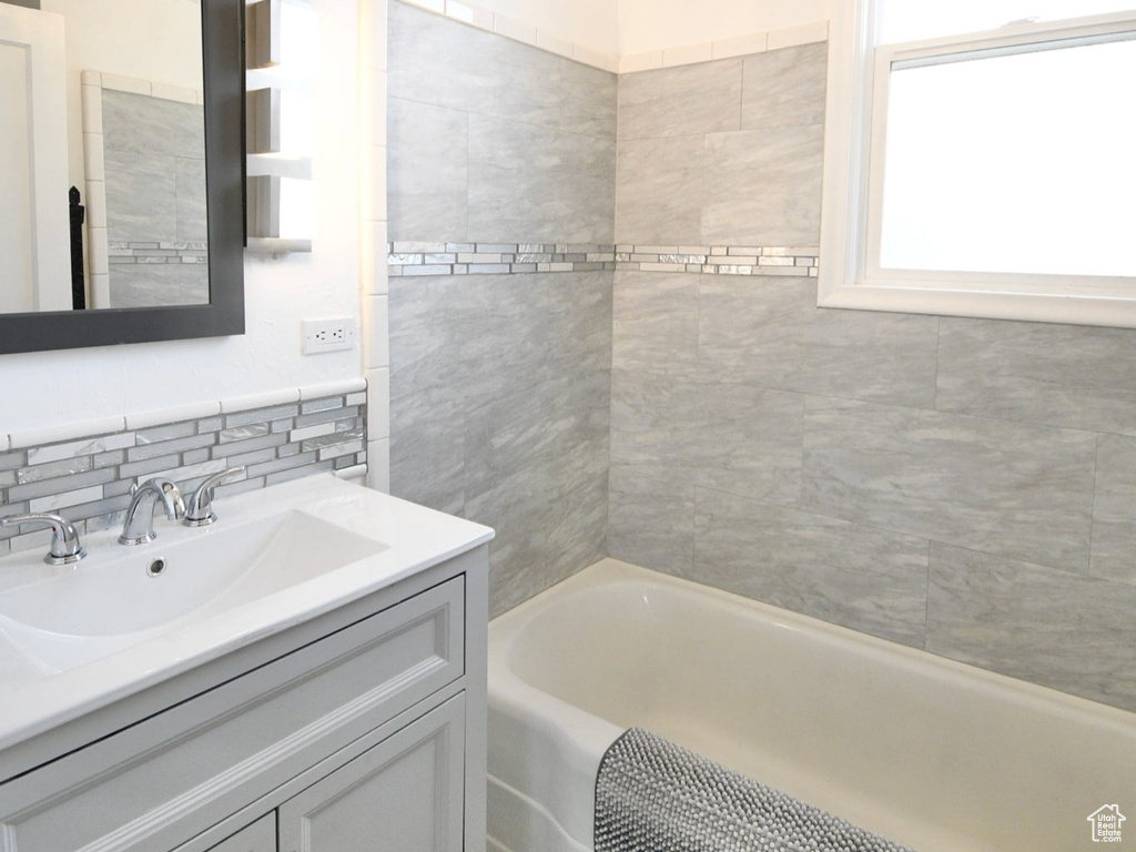 Bathroom featuring a chandelier, tiled shower / bath, tile flooring, and large vanity