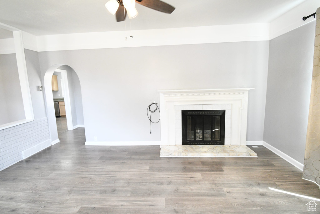 Unfurnished living room with ceiling fan, hardwood / wood-style flooring, and a high end fireplace