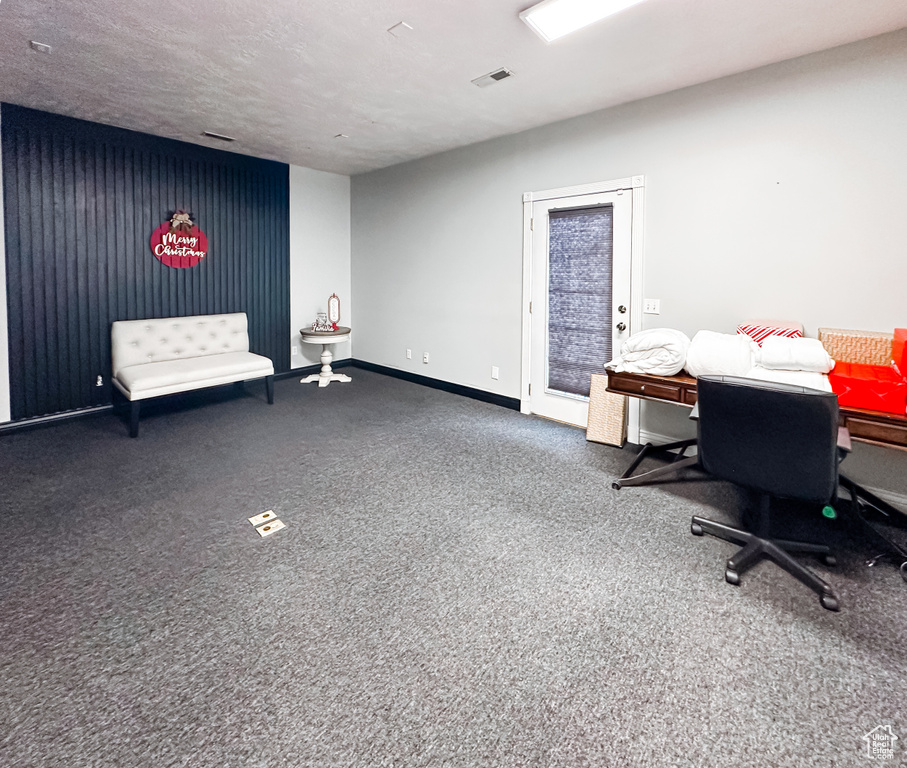Office space with dark colored carpet and a textured ceiling