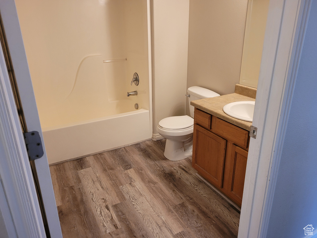 Full bathroom with washtub / shower combination, wood-type flooring, vanity, and toilet