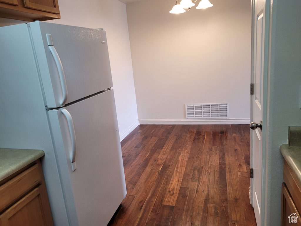 Kitchen featuring white fridge and dark wood-type flooring