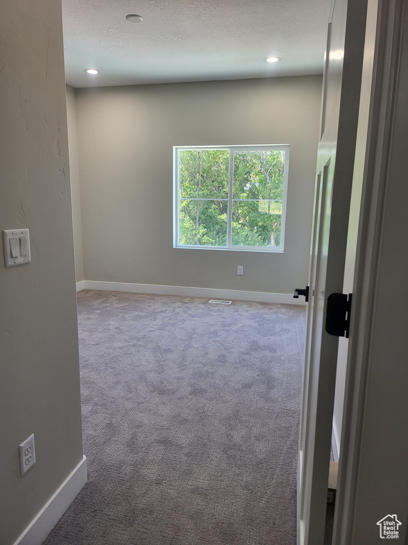 Empty room featuring a textured ceiling and carpet floors