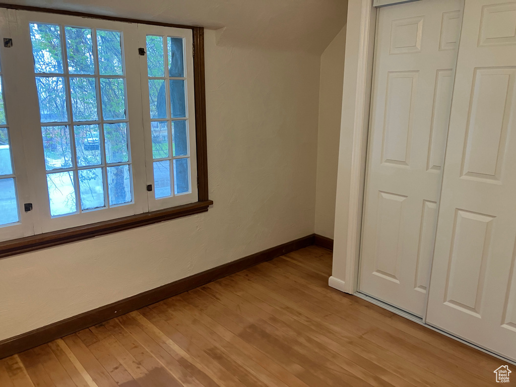 Unfurnished bedroom featuring a closet, light hardwood / wood-style floors, and multiple windows