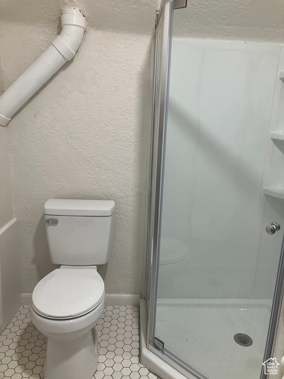 Bathroom with toilet, tile floors, and a shower with shower door