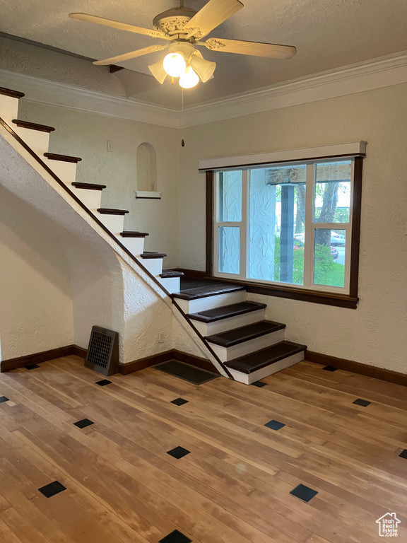 Stairway with crown molding, ceiling fan, and hardwood / wood-style floors