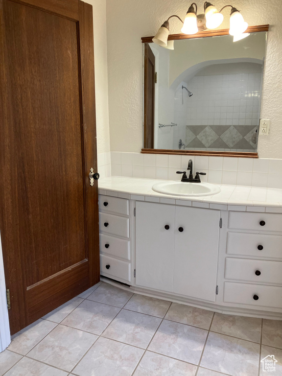 Bathroom featuring tile flooring, vanity, and tasteful backsplash