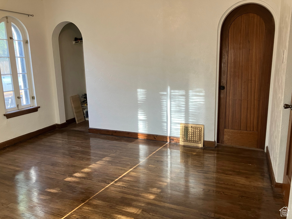 Empty room with dark hardwood / wood-style floors and a wealth of natural light