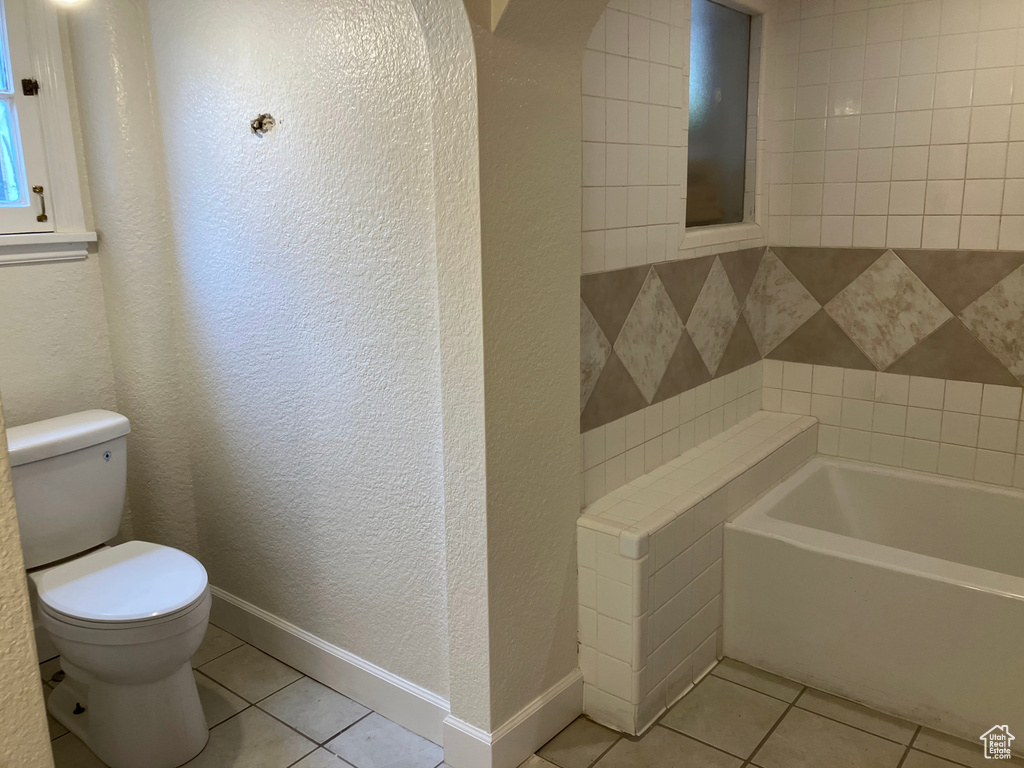 Bathroom with a bathtub, toilet, and tile flooring