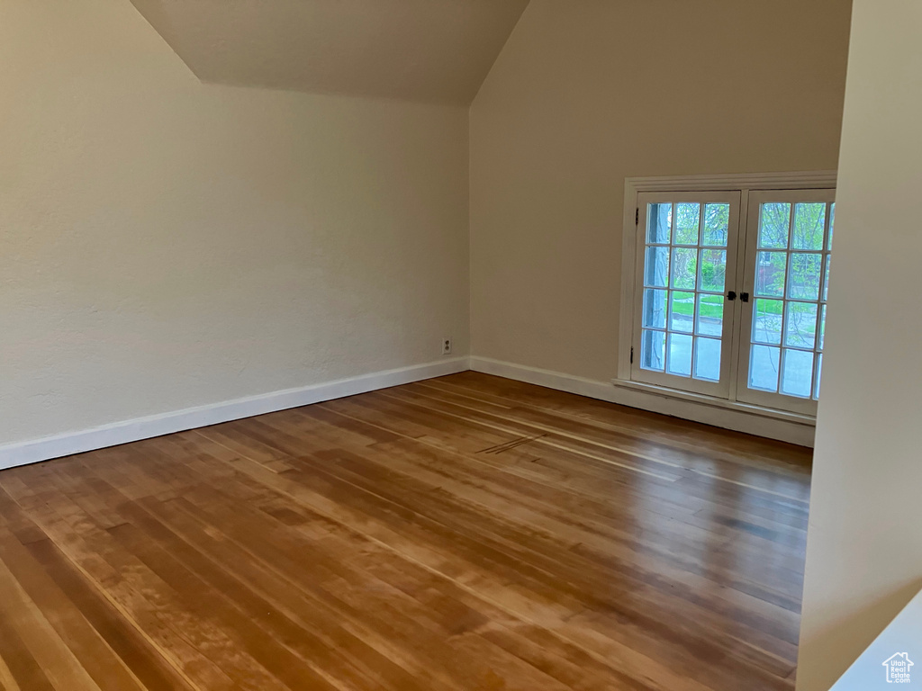Unfurnished room with hardwood / wood-style flooring, high vaulted ceiling, and french doors