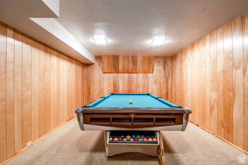 Rec room with a textured ceiling, wood walls, carpet flooring, and pool table