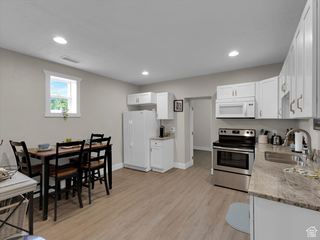 Kitchen featuring sink, white appliances, white cabinetry, and light hardwood / wood-style flooring