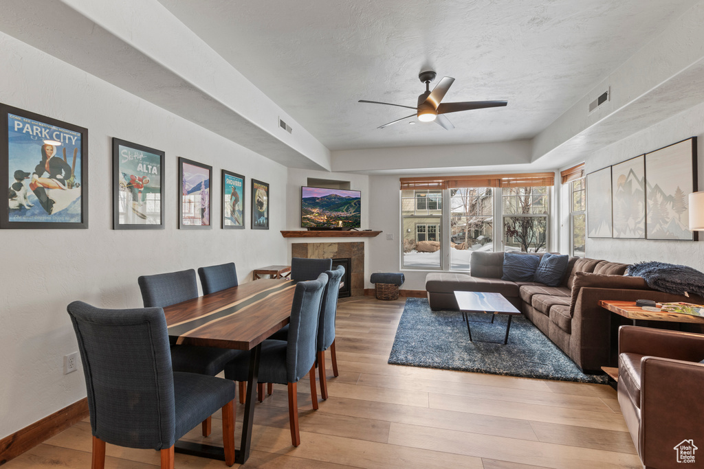Dining area featuring a tiled fireplace, light hardwood / wood-style flooring, and ceiling fan