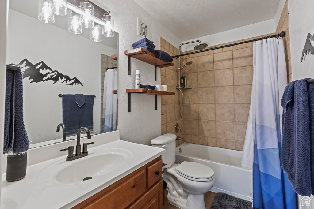 Full bathroom with vanity, shower / tub combo, and toilet