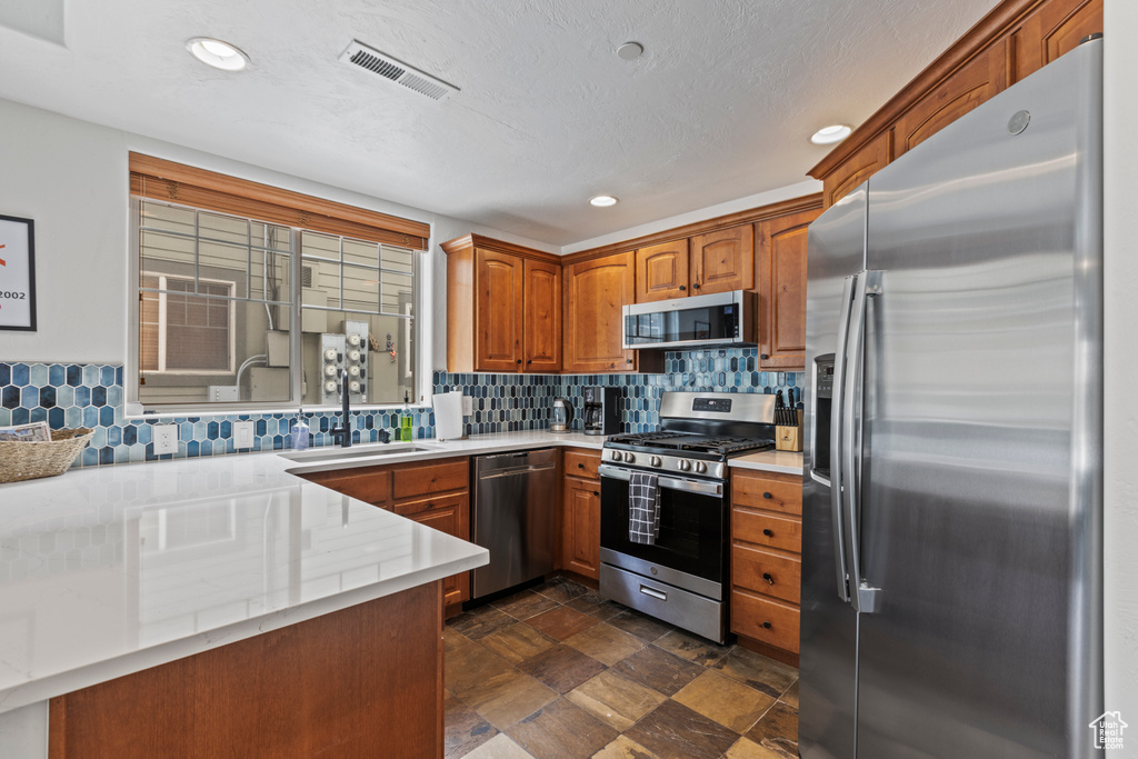 Kitchen with backsplash, dark tile floors, stainless steel appliances, and sink