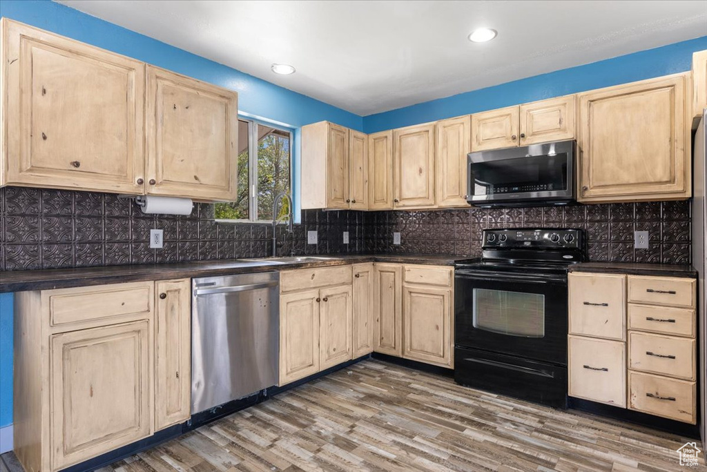 Kitchen featuring hardwood / wood-style floors, sink, appliances with stainless steel finishes, and backsplash