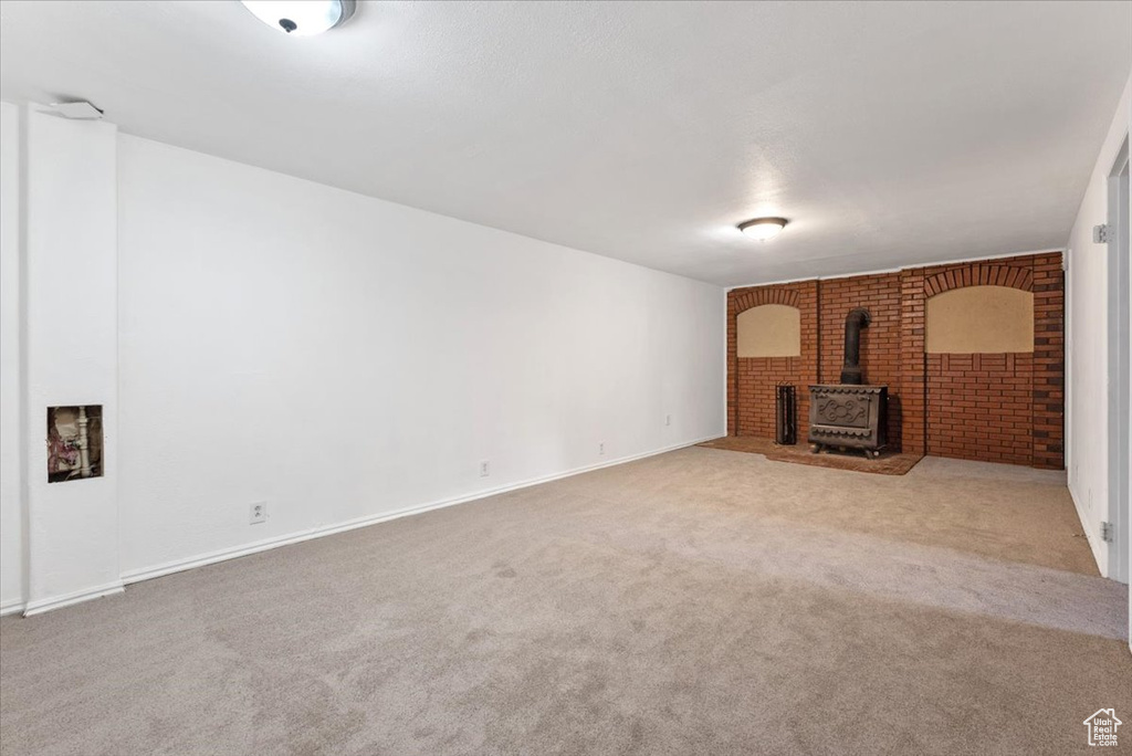 Unfurnished living room featuring a wood stove and carpet